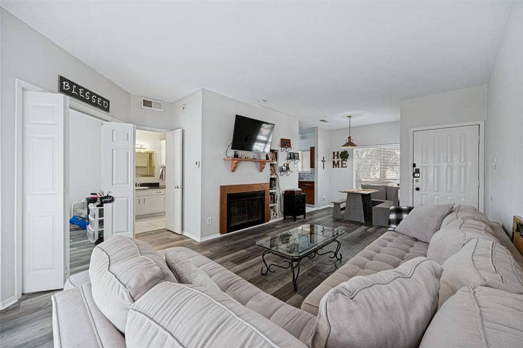 5550 Spring Valley Road, #C21, Dallas, TX 75254 Wood-finish flooring throughout, fireplace with a wood mantle, recessed lighting, and a paneled entry door