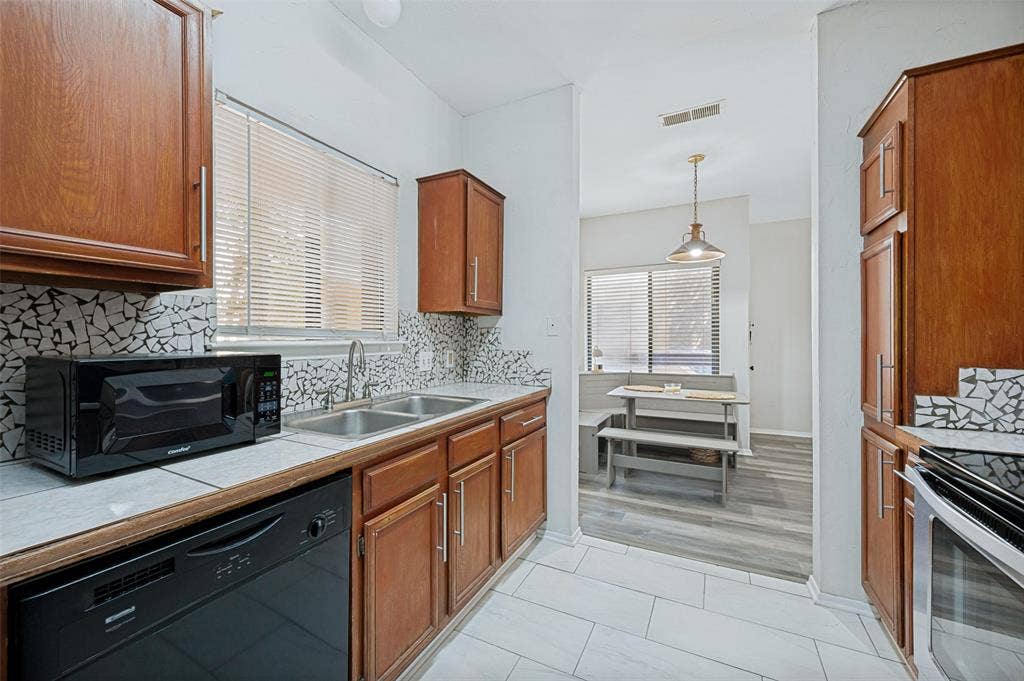 5550 Spring Valley Road, #C21, Dallas, TX 75254 Kitchen featuring wood cabinetry, a double basin sink, and a patterned tile backsplash