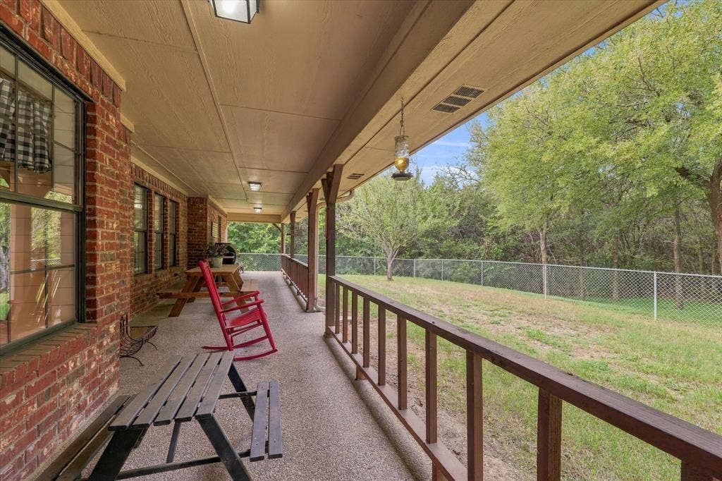 1600 Fox Ridge Road, Lorena, TX 76655 Covered porch featuring brick exterior siding, concrete flooring, and a wood railing overlooking a chain-link fenced backyard