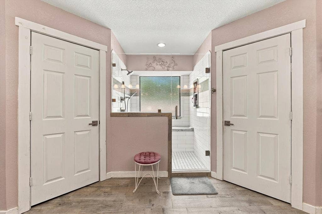 1600 Fox Ridge Road, Lorena, TX 76655 Walk-in shower featuring white subway tile, a decorative tile inlay, a glass door, and wood-finish flooring