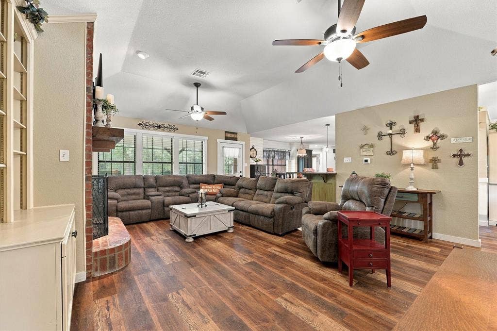 1600 Fox Ridge Road, Lorena, TX 76655 Vaulted ceiling featuring dual ceiling fans, wood-finish flooring, and a brick-surround fireplace with a timber mantel