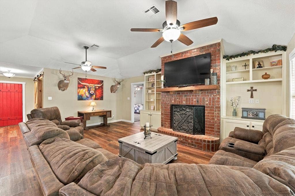 1600 Fox Ridge Road, Lorena, TX 76655 Vaulted ceilings, brick fireplace with a wood mantel, built-in shelving, wood-finish flooring, and dual ceiling fans