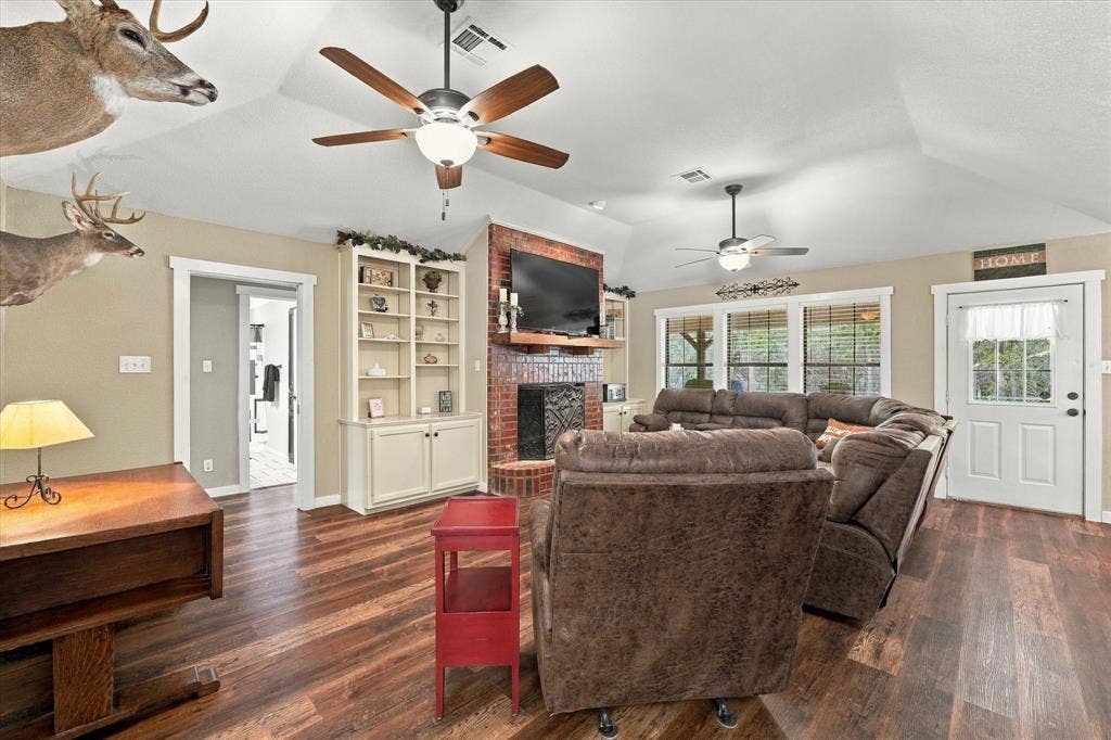 1600 Fox Ridge Road, Lorena, TX 76655 Vaulted ceilings featuring dual ceiling fans, red brick fireplace with wooden mantel, and built-in cabinetry