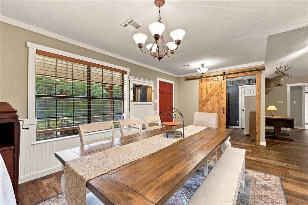 1600 Fox Ridge Road, Lorena, TX 76655 Dining area featuring wood-finish flooring, beadboard wainscoting, a custom sliding barn door, and a five-light chandelier