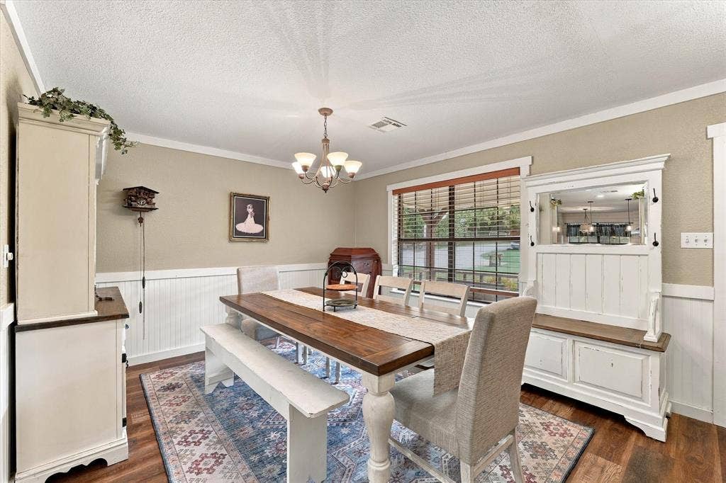 1600 Fox Ridge Road, Lorena, TX 76655 Dining area featuring wood-finish flooring, white wainscoting, an integrated multi-light chandelier, and a large picture window with wooden blinds