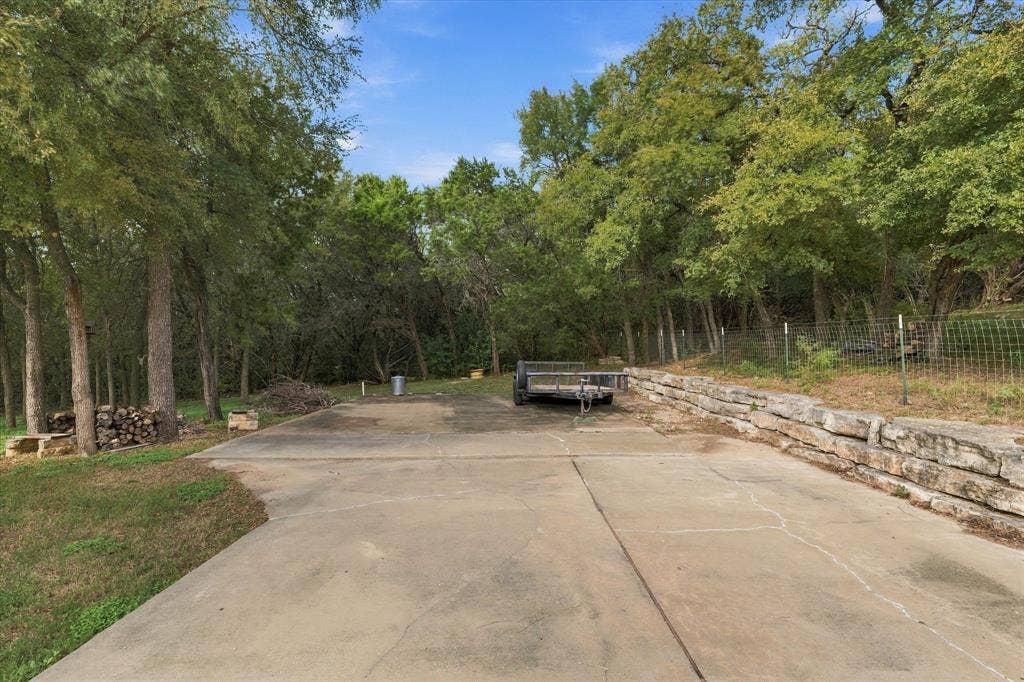 1600 Fox Ridge Road, Lorena, TX 76655 Extensive concrete pad featuring tiered natural stone retaining walls and mature canopy trees
