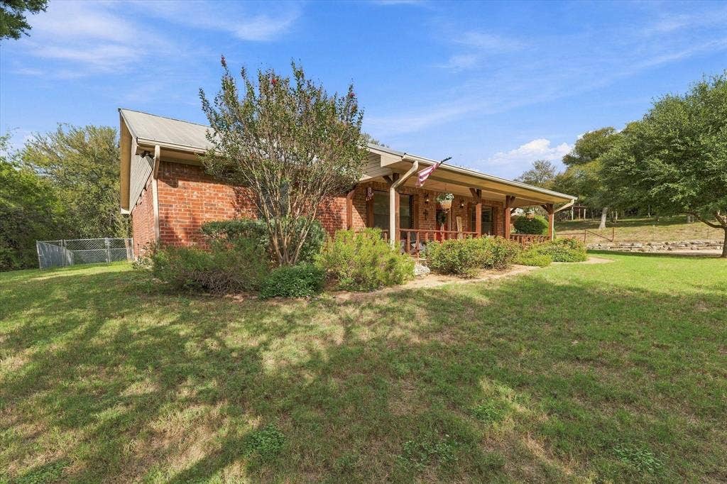 1600 Fox Ridge Road, Lorena, TX 76655 Red brick exterior featuring a metal roof and a covered front porch with timber supports