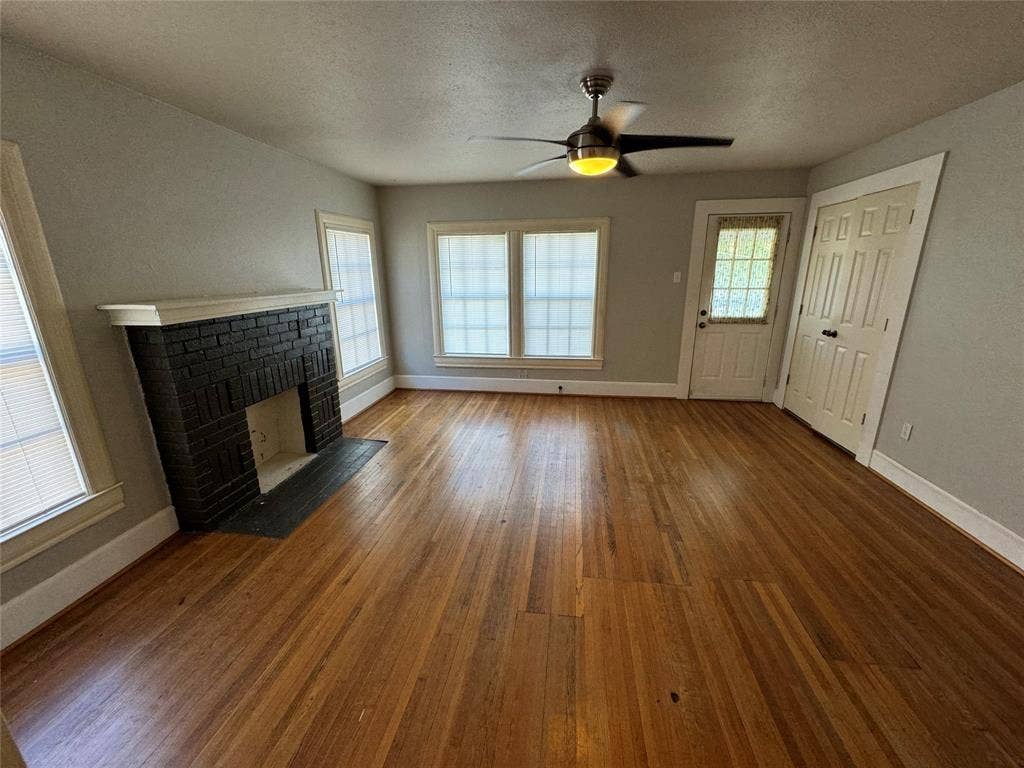 5321 Reiger Avenue, #4, Dallas, TX 75214 Unfurnished living room featuring a textured ceiling, ceiling fan, hardwood / wood-style flooring, and a fireplace