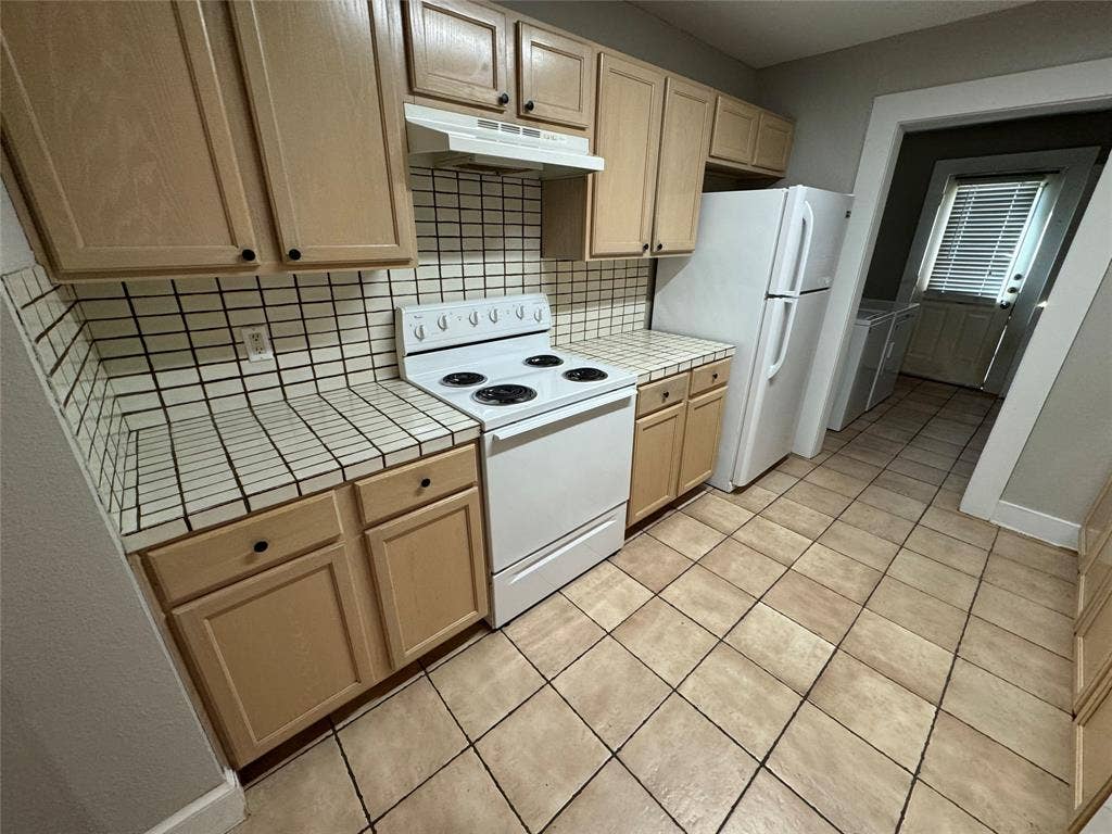 5321 Reiger Avenue, #4, Dallas, TX 75214 Kitchen featuring white appliances, light tile patterned floors, light brown cabinets, and tasteful backsplash