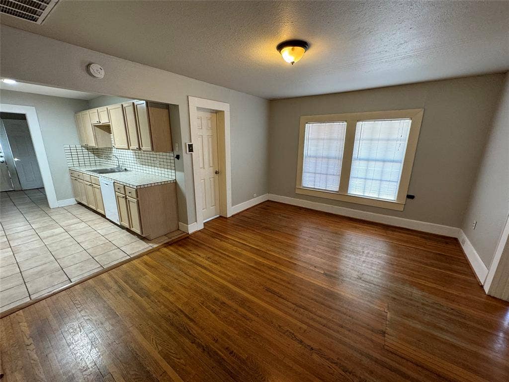 5321 Reiger Avenue, #4, Dallas, TX 75214 Kitchen featuring a textured ceiling, dishwasher, light hardwood / wood-style floors, sink, and decorative backsplash