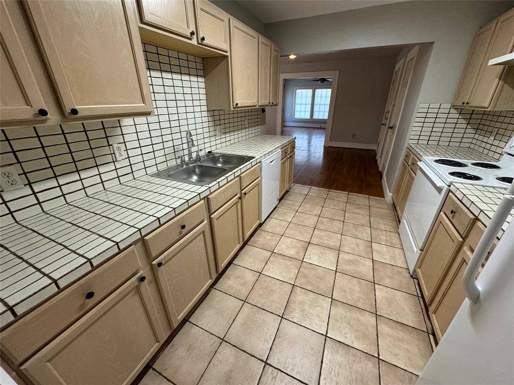 5321 Reiger Avenue, #4, Dallas, TX 75214 Kitchen with white appliances, light hardwood / wood-style flooring, tile countertops, sink, and decorative backsplash