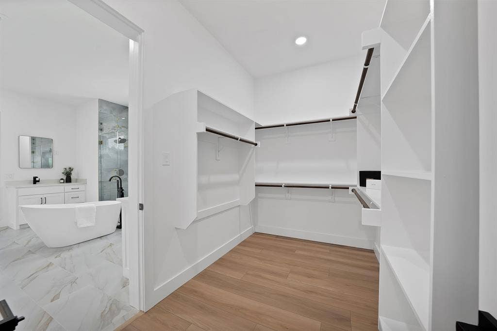 Walk-in closet featuring wood-finish flooring, built-in shelving, and hanging rods