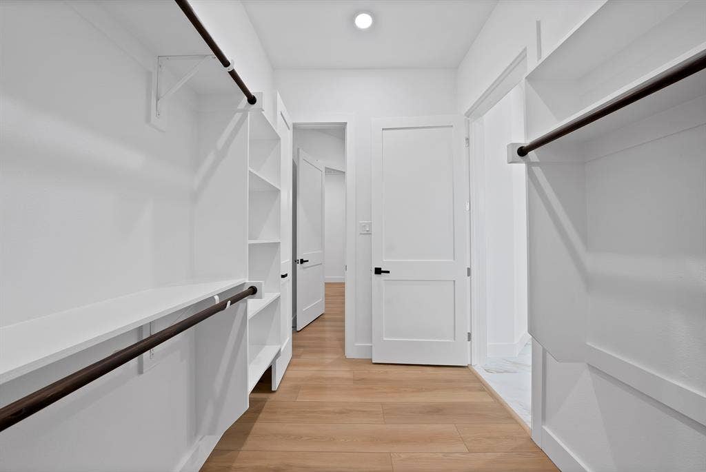 Built-in closet shelving and hanging rods, wood-finish flooring, white paneled doors, and recessed lighting