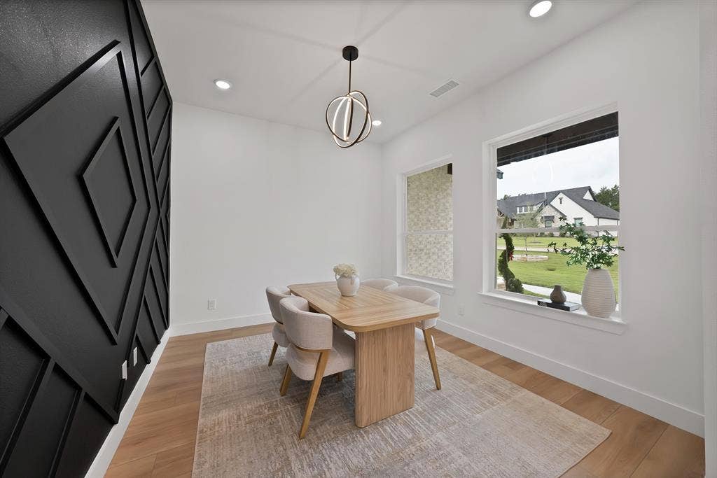 Hardwood-style flooring, sculptural accent wall, recessed lighting, contemporary chandelier, and large windows