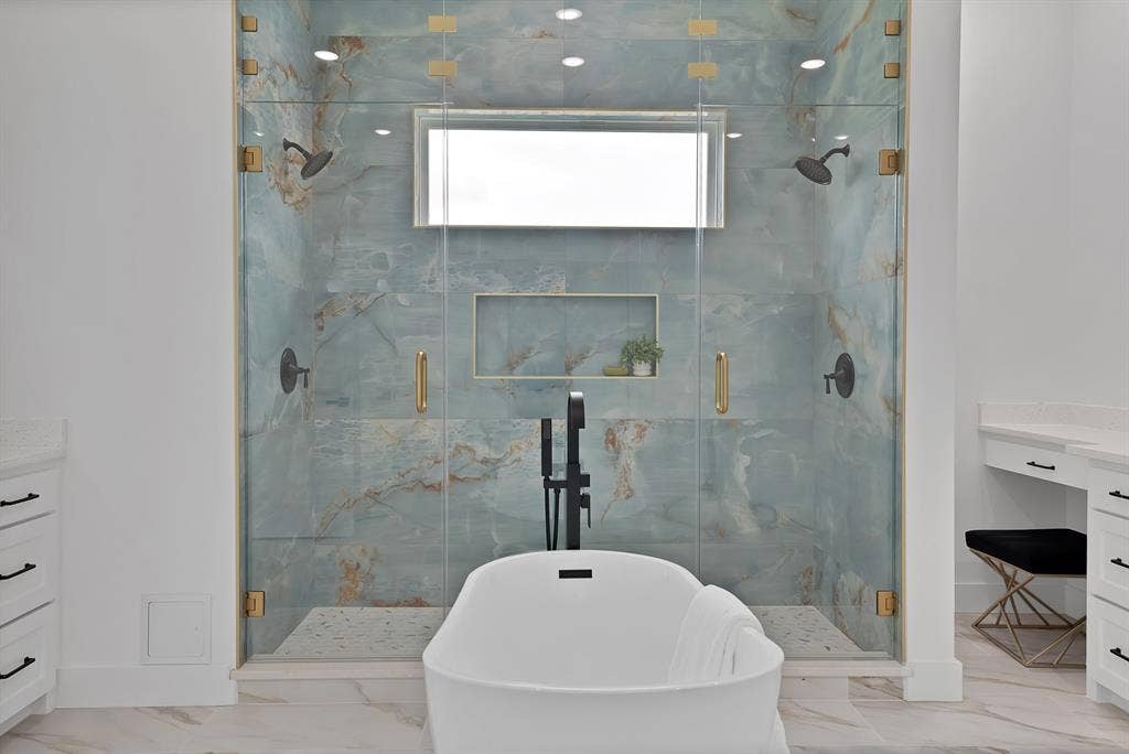 Spacious walk-in shower with floor-to-ceiling glass enclosure, dual shower heads, and an integrated niche