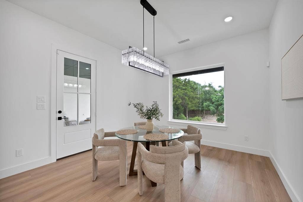 Light wood-finish flooring, a contemporary chandelier, recessed ceiling lighting, a large window, and a white paneled door with glass inserts
