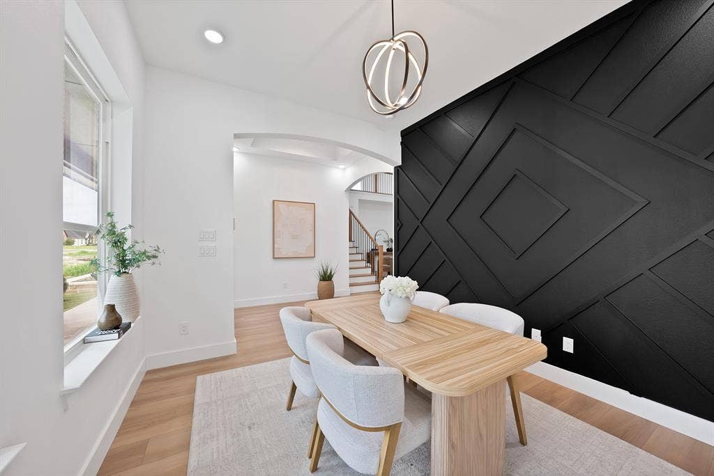 Recessed lighting, wood-finish flooring, and a decorative accent wall with geometric paneling
