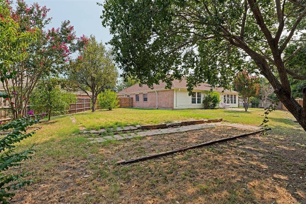 1412 Sleepy Hollow Drive, Allen, TX 75002 Expansive backyard featuring a wood fence, mature trees, and a brick and siding exterior