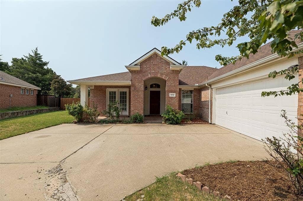 1412 Sleepy Hollow Drive, Allen, TX 75002 Brick exterior with an arched entryway, attached two-car garage, and a concrete driveway