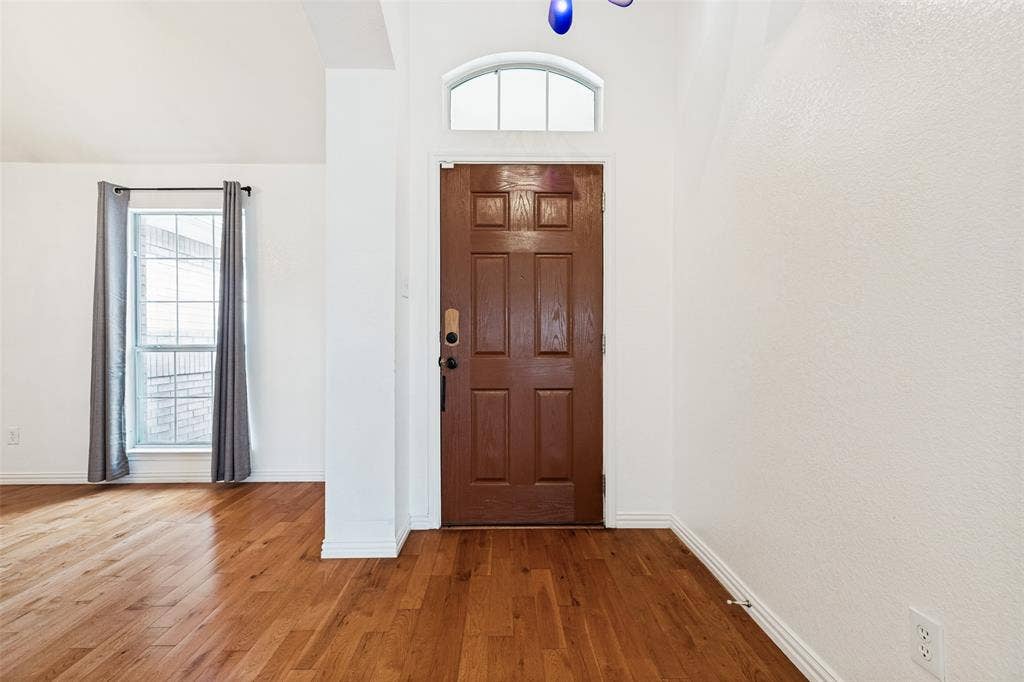 1412 Sleepy Hollow Drive, Allen, TX 75002 Paneled entry door with an arched transom window, wood-finish flooring, and white walls