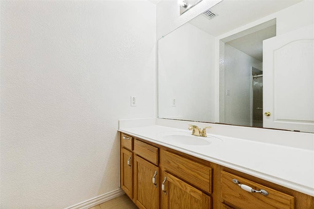 1412 Sleepy Hollow Drive, Allen, TX 75002 Vanity with wood cabinetry, integrated sink, and expansive wall-mounted mirror