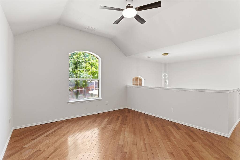 1416 Sunrise Lane, Sachse, TX 75048 Vaulted ceiling, arched window, wood-finish flooring, ceiling fan, and open railing