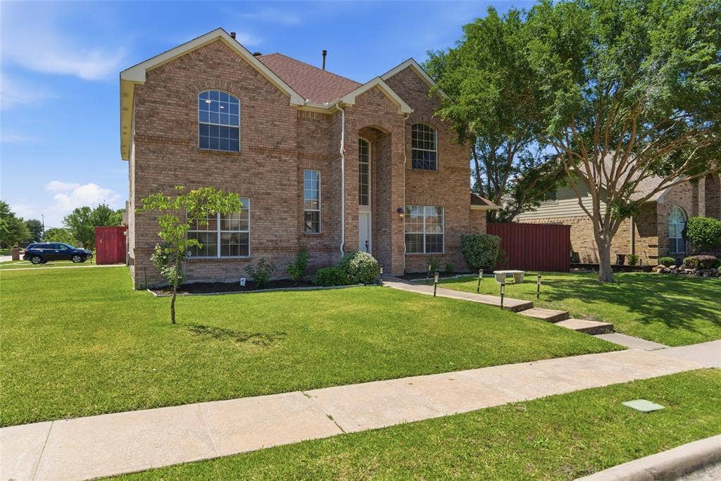 1416 Sunrise Lane, Sachse, TX 75048 Brick exterior with arched windows, gabled roof, and a concrete walkway