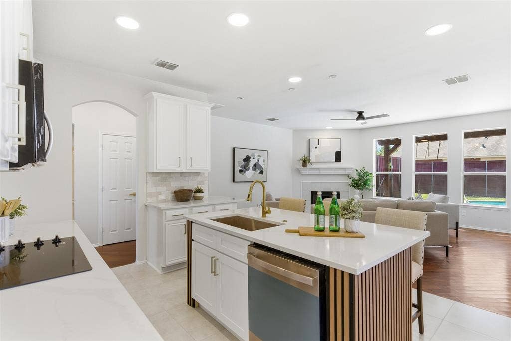 1416 Sunrise Lane, Sachse, TX 75048 Open-concept living area featuring a kitchen island with seating, a built-in cooktop, and a fireplace in the living space