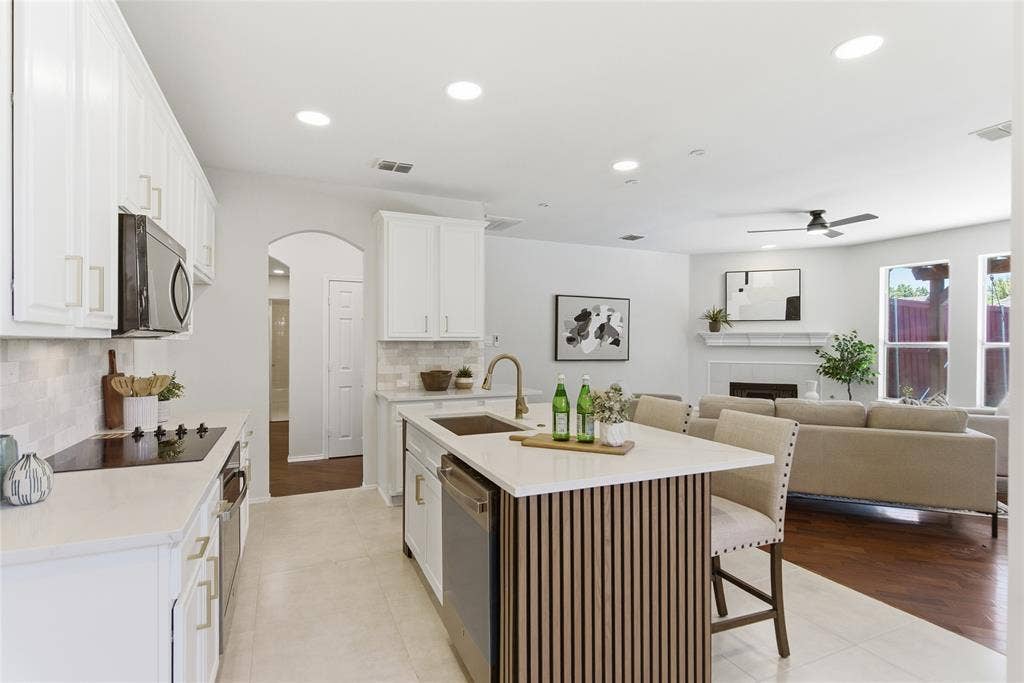 1416 Sunrise Lane, Sachse, TX 75048 Kitchen featuring white cabinetry, a central island with slatted wood detailing, stainless steel appliances, and light-toned countertops