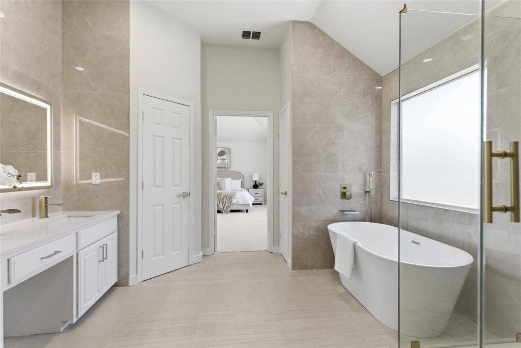 1416 Sunrise Lane, Sachse, TX 75048 Freestanding soaking tub, frameless glass shower enclosure, vanity with integrated sink, illuminated mirror, and large format tile flooring