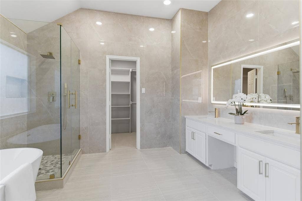 1416 Sunrise Lane, Sachse, TX 75048 Dual vanity with white cabinetry, gold-finish fixtures, and an integrated illuminated mirror