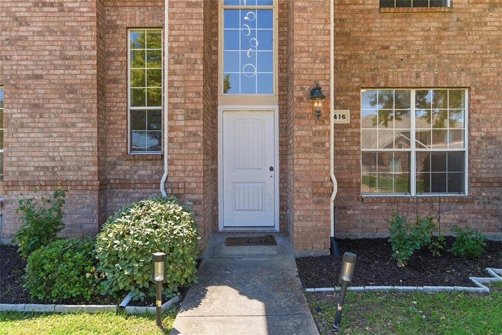 1416 Sunrise Lane, Sachse, TX 75048 Brick exterior featuring a white entry door with an arched transom