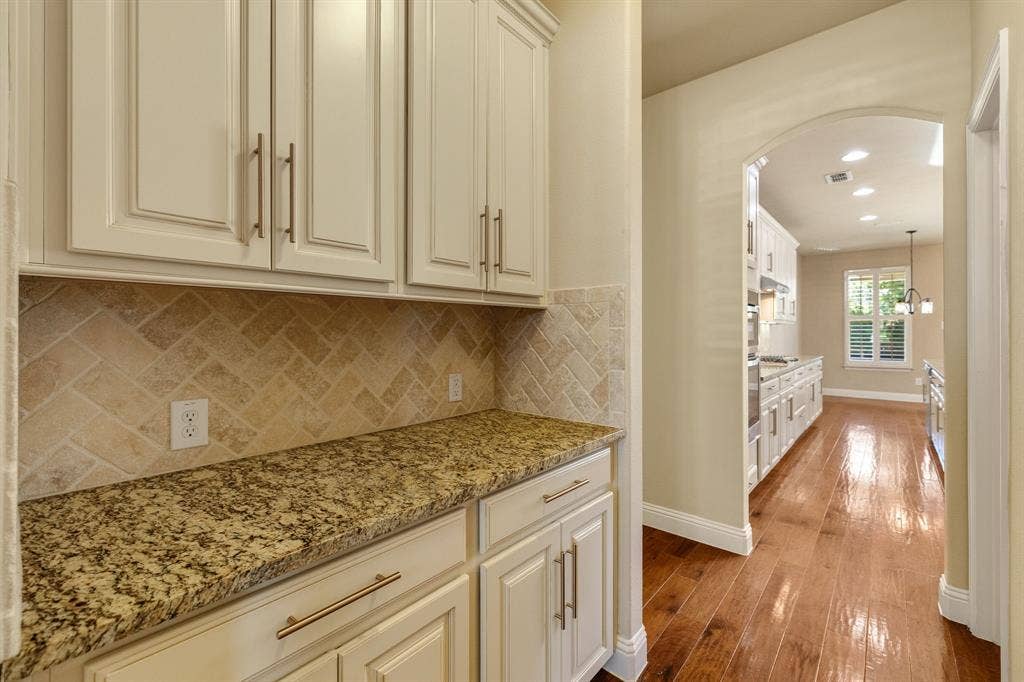 1049 Mesa Crest Drive, Fort Worth, TX 76052 Butlers pantry featuring white cabinetry with brushed nickel pulls, granular countertop, and a herringbone-patterned backsplash