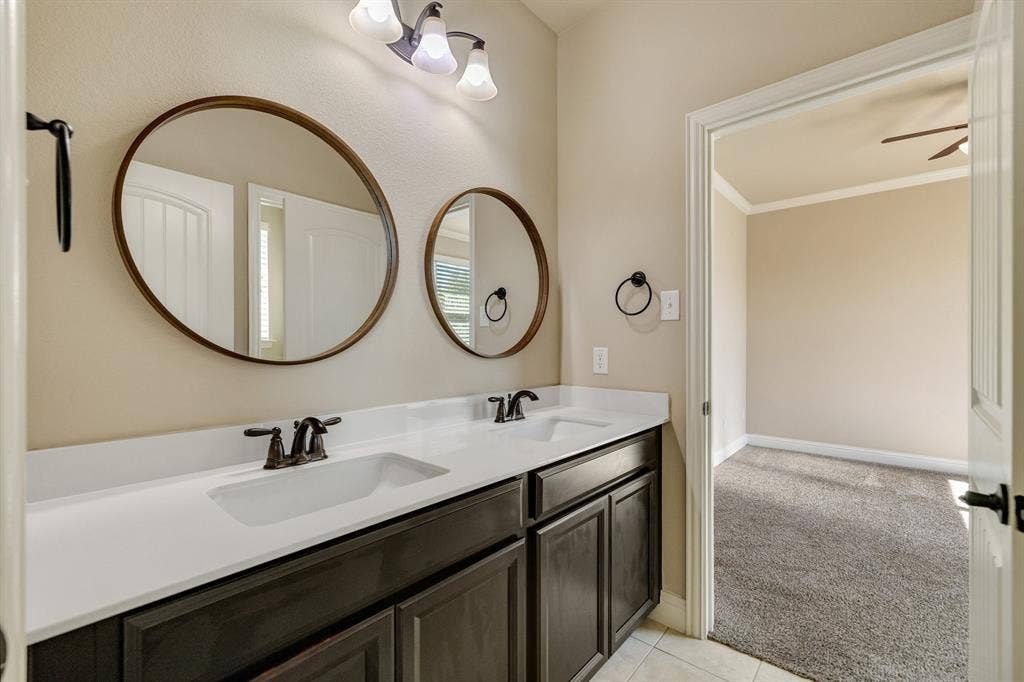 1049 Mesa Crest Drive, Fort Worth, TX 76052 Jack and Jill bathroom featuring dual vanity with dual integrated sinks, dark wood-finish cabinetry, and circular framed mirrors