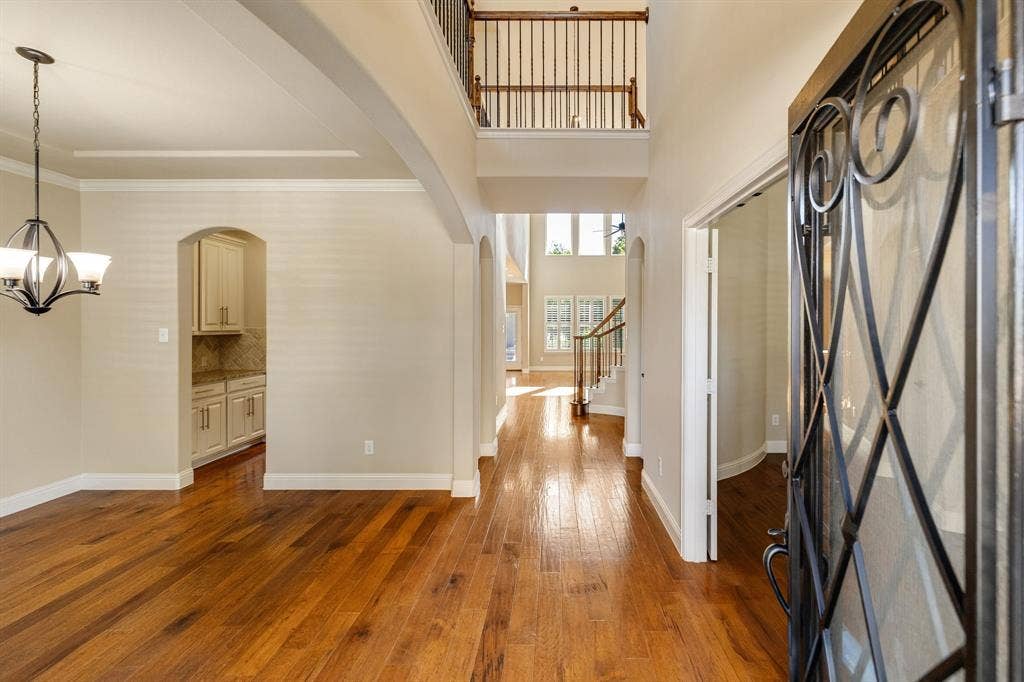 1049 Mesa Crest Drive, Fort Worth, TX 76052 Hardwood flooring throughout, a two-story foyer, iron-spindled balustrade, and an arched entryway to butlers pantry Off of Formal Dining area.