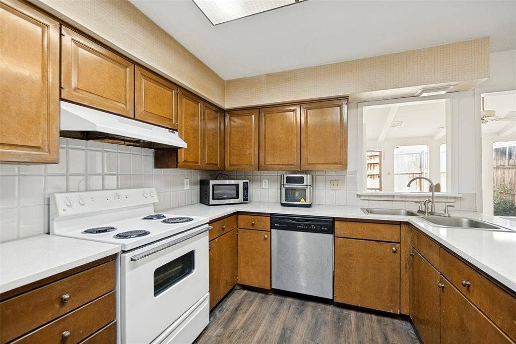 11916 Leisure Drive, Dallas, TX 75243 Wood-finish flooring, wood cabinetry, white tile backsplash, white countertops, and a double basin stainless steel sink