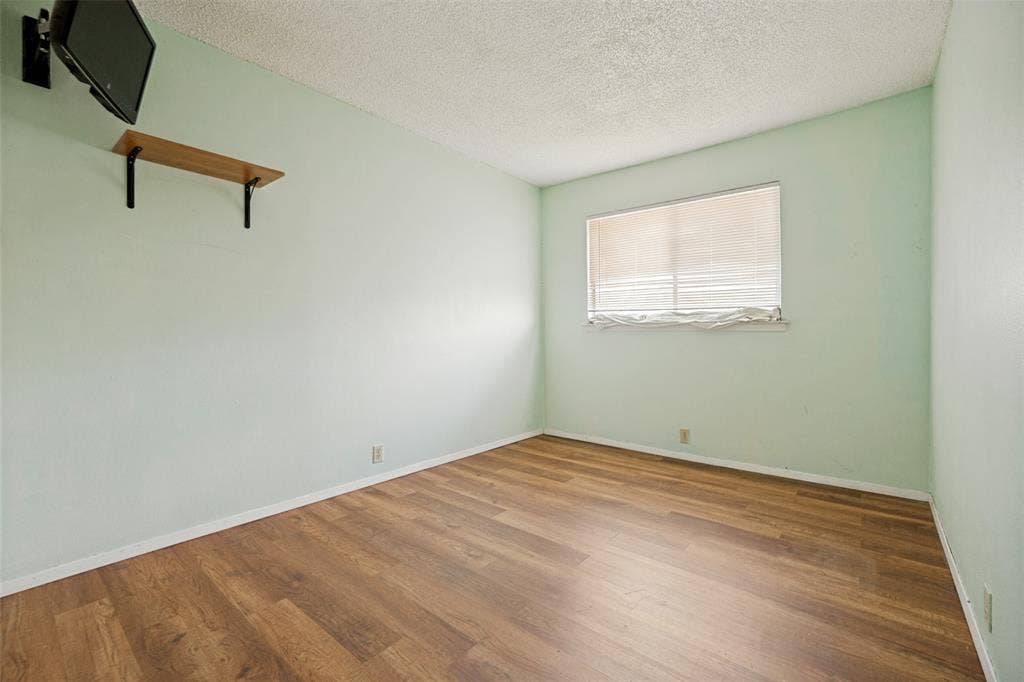 11916 Leisure Drive, Dallas, TX 75243 Wood-finish flooring, light-toned walls, and a built-in wall shelf