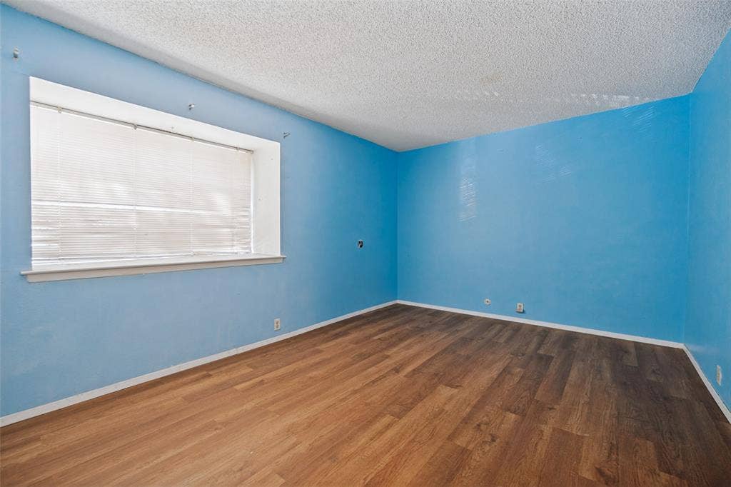 11916 Leisure Drive, Dallas, TX 75243 Wood-finish flooring with a window featuring white blinds