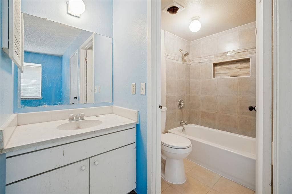 11916 Leisure Drive, Dallas, TX 75243 Bathroom featuring a vanity with an integrated sink, a large wall-mounted mirror, and a tub/shower combination with tiled walls and a recessed niche