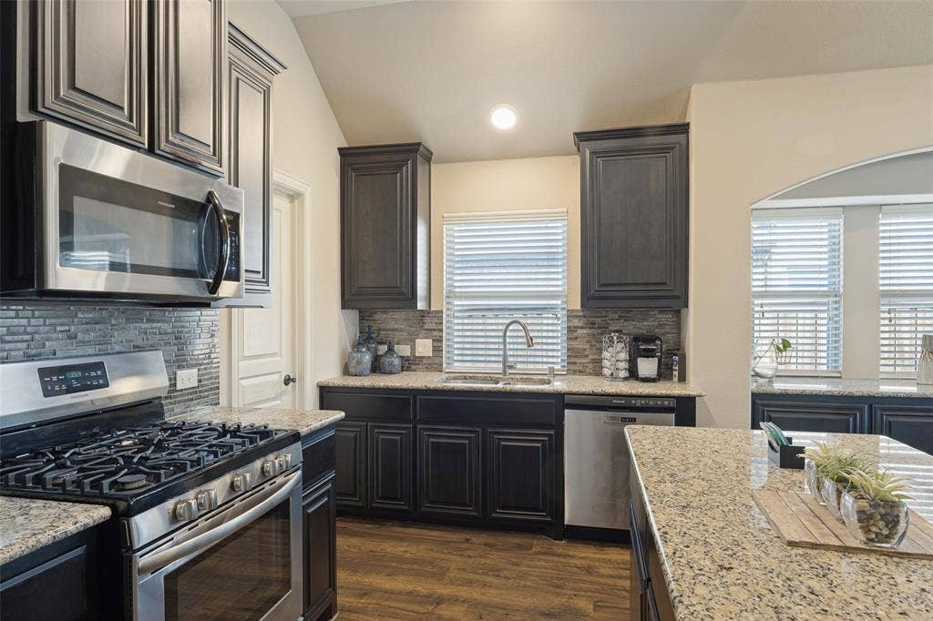 Functional galley kitchen with stainless appliances, dual sink and walk-in pantry.