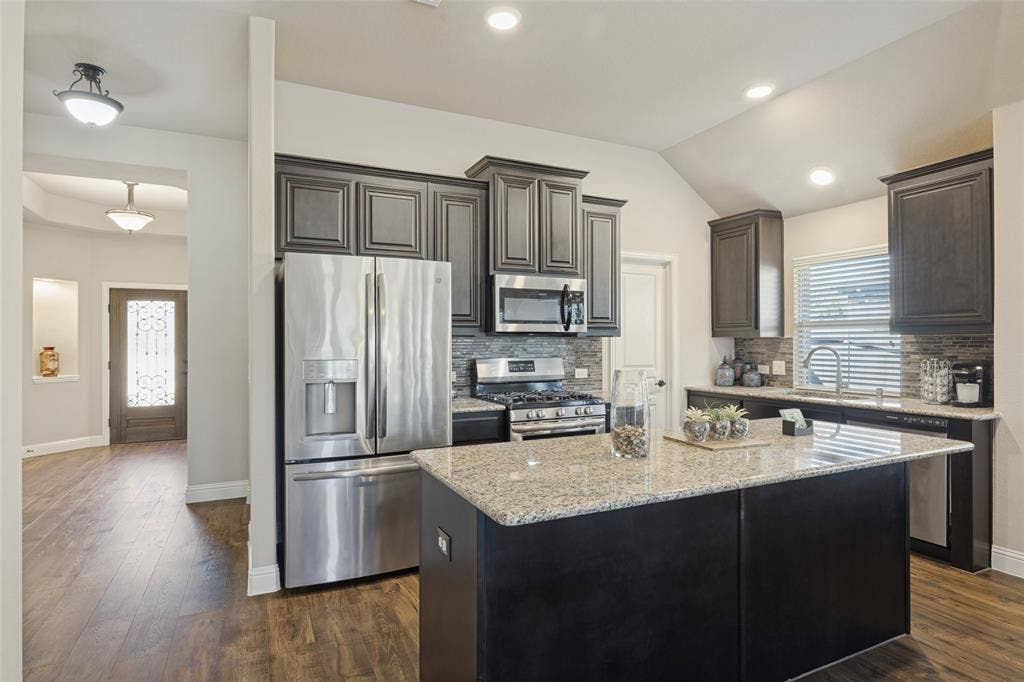 Large island in kitchen with granite counter top.