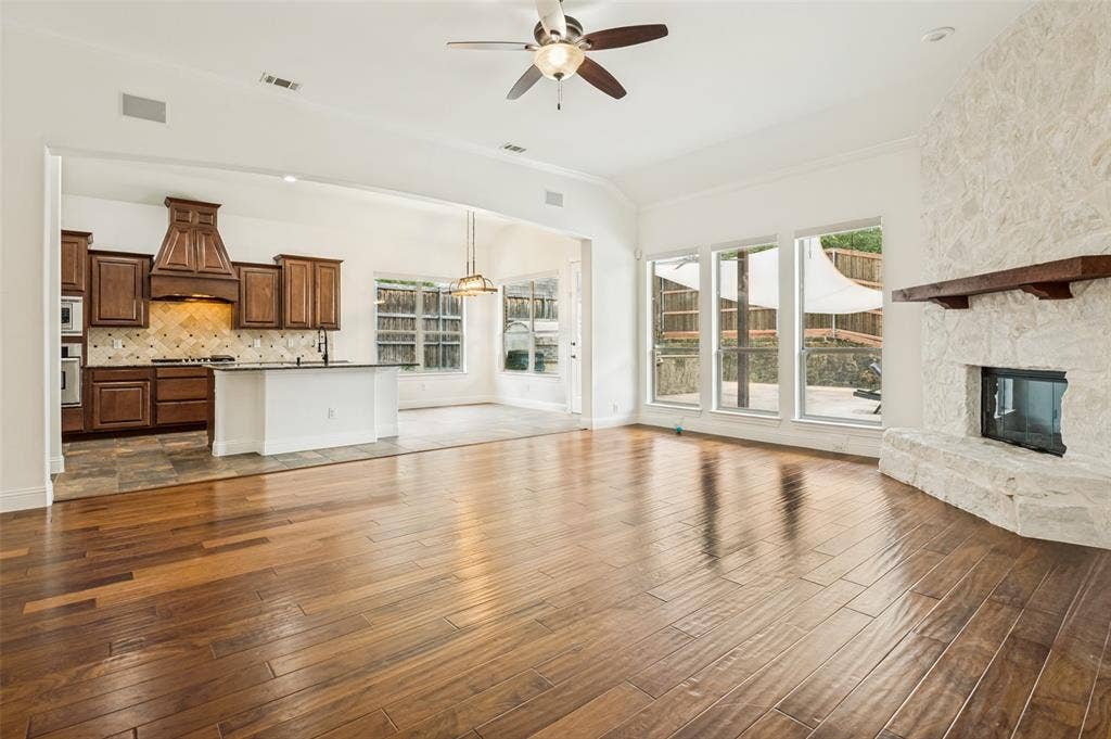 6734 Trailblazer Way, Dallas, TX 75236 Expansive living area featuring wood-finish flooring, a stone fireplace with a wood mantle, and a ceiling fan