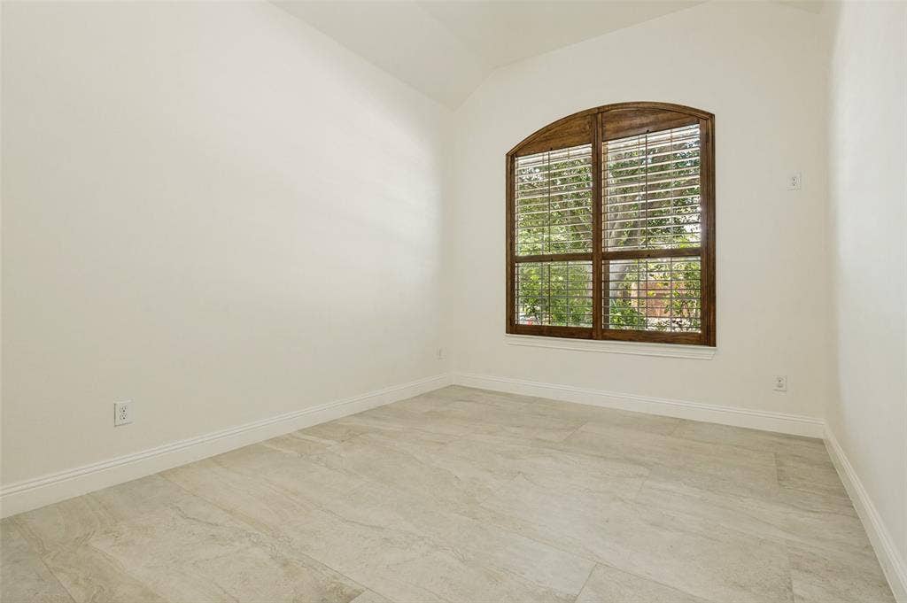 6734 Trailblazer Way, Dallas, TX 75236 Arched window with wood frame and plantation shutters, light-colored tile flooring, and white walls