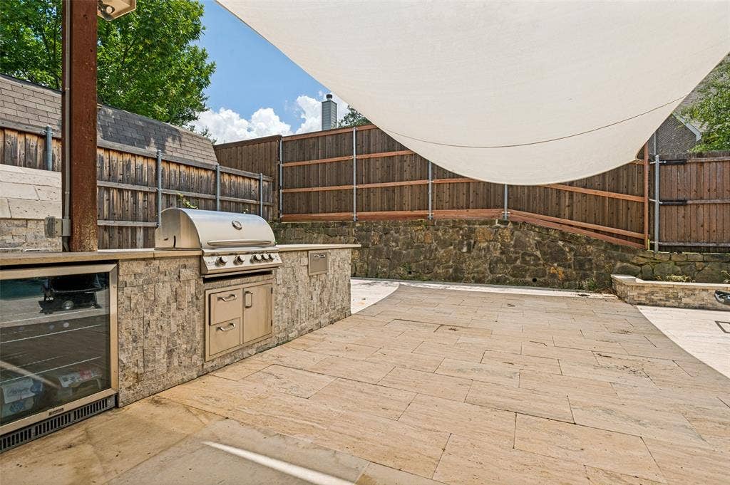 6734 Trailblazer Way, Dallas, TX 75236 Outdoor kitchen featuring an integrated grill, beverage refrigerator, and stone-clad cabinetry
