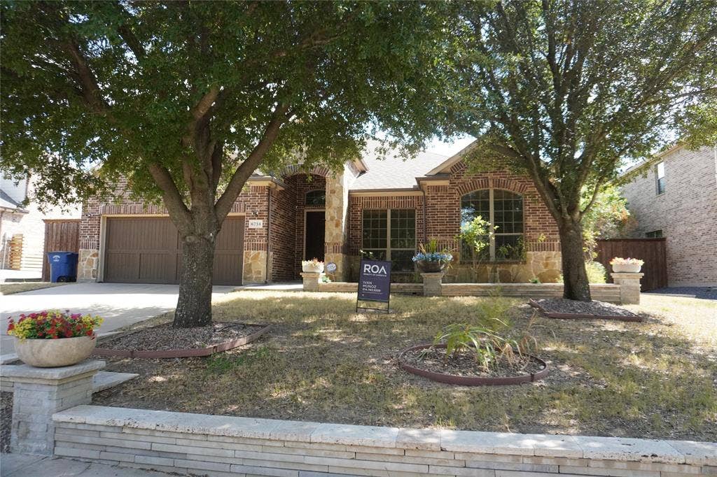 6734 Trailblazer Way, Dallas, TX 75236 Brick and stone facade residence with an arched entryway, arched window, and attached garage