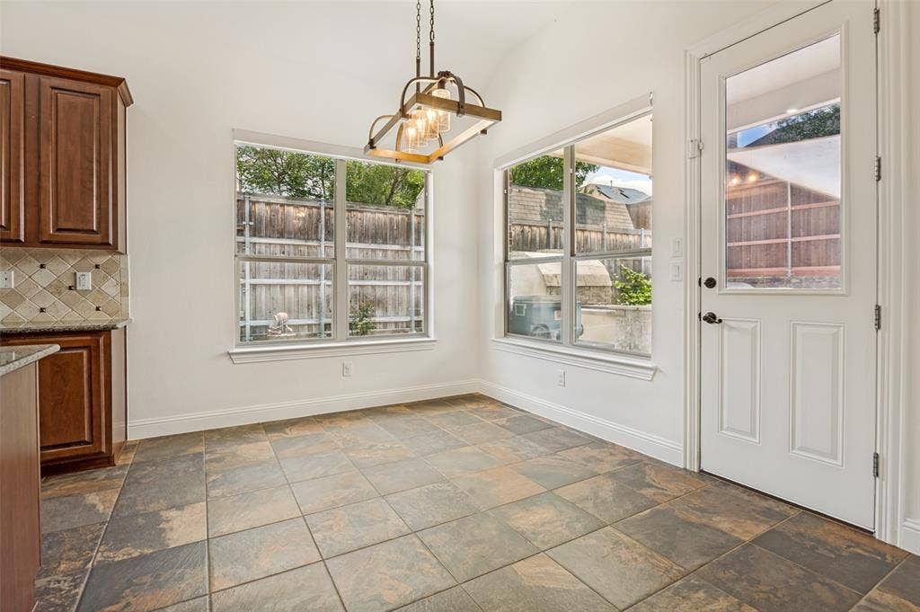 6734 Trailblazer Way, Dallas, TX 75236 Vaulted ceiling with an industrial-style chandelier, tile flooring, built-in cabinetry, granite-style countertop, and a glass-paneled door