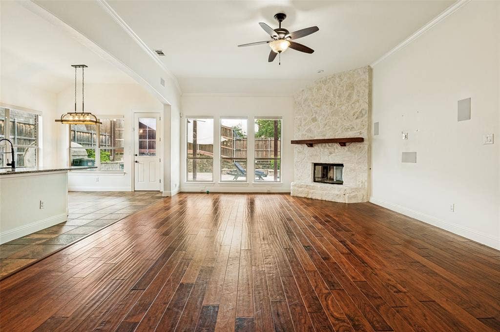 6734 Trailblazer Way, Dallas, TX 75236 Wood-finish flooring, stone fireplace with wood mantle, multiple windows, ceiling fan, and recessed speakers