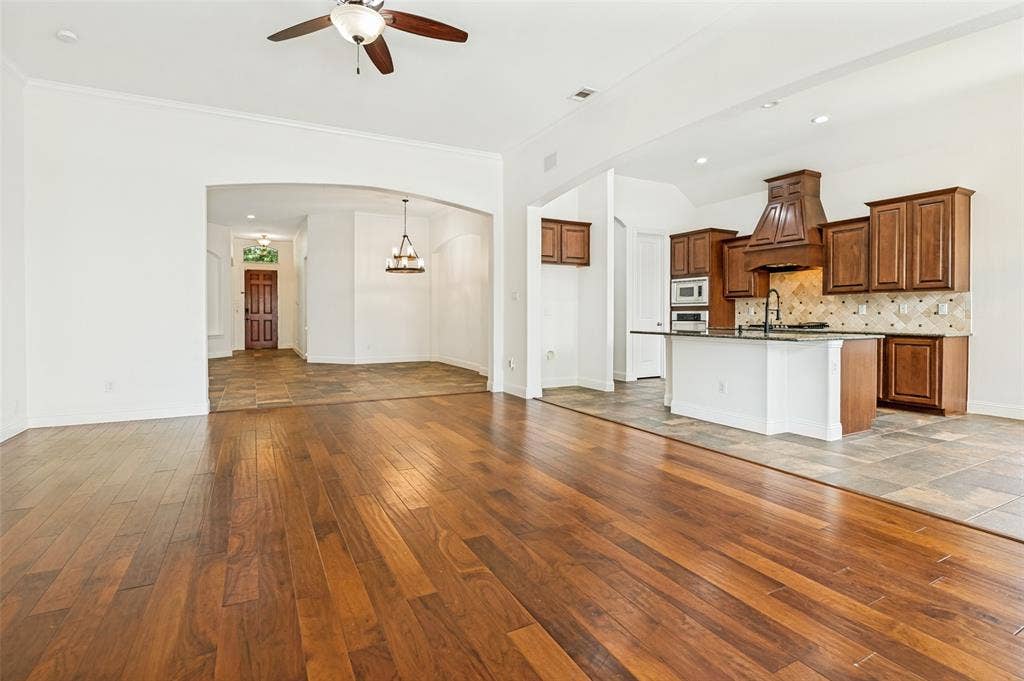 6734 Trailblazer Way, Dallas, TX 75236 Hardwood flooring, kitchen island with dark countertop, stainless steel built-in appliances, custom wood range hood, and tile backsplash