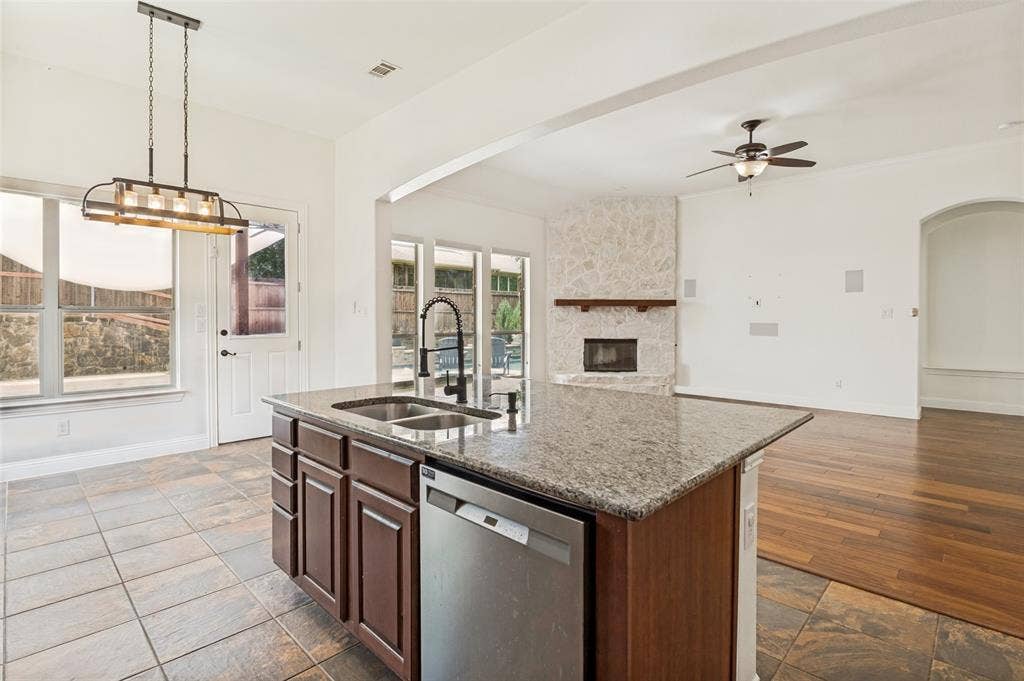 6734 Trailblazer Way, Dallas, TX 75236 Kitchen island with granite countertop and dual basin sink, stainless steel dishwasher, tile flooring, and a decorative light fixture