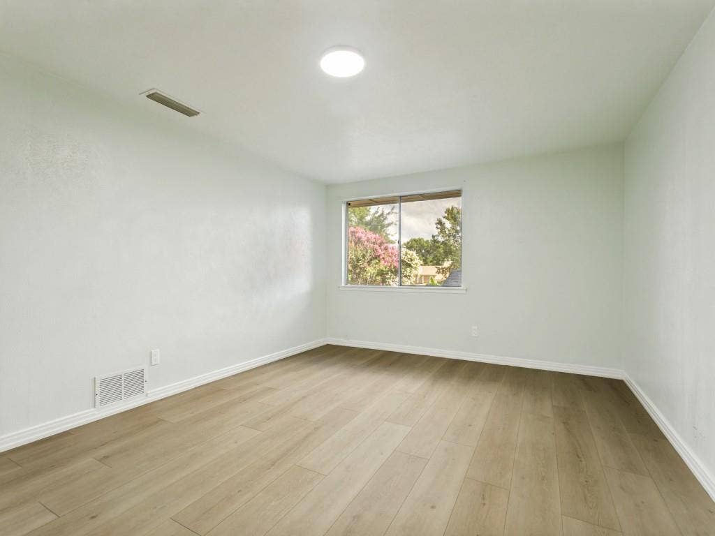 2018 Vail Drive, Garland, TX 75044 Wood-finish flooring, white baseboards, window with exterior scenery, ceiling-mounted light fixture, and white wall finishes